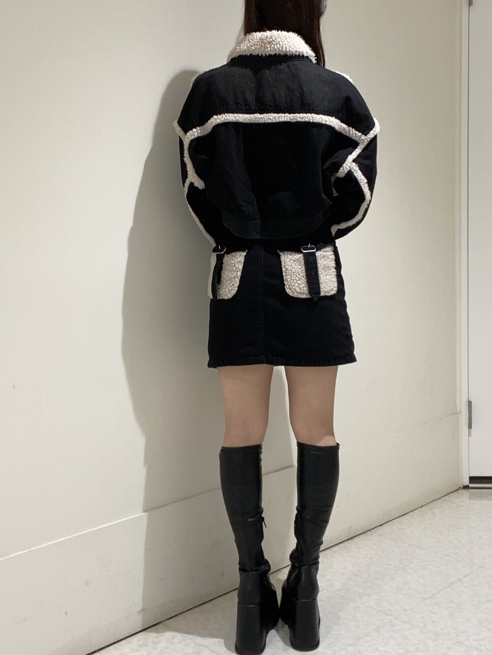 ブラック系のブルゾン、ブラック系のデニムスカート、ブラック系のブーツを着用したレディースの秋コーディネートの3枚目の写真