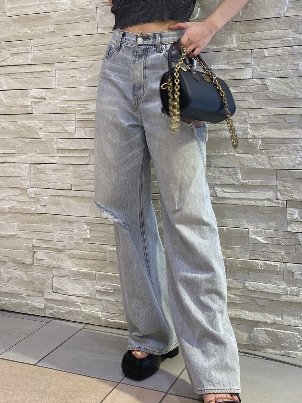 ブラック系のニット/セーター、ブルー系のデニムパンツ、その他のショルダーバッグを着用したレディースの夏コーディネートの6枚目の写真