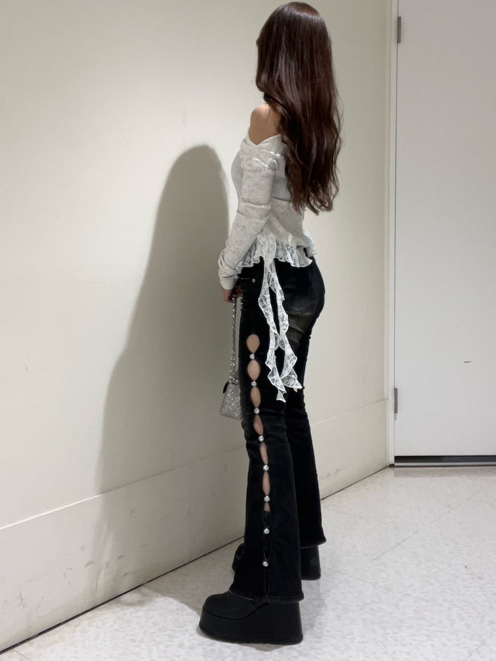 シルバー系のショルダーバッグ、ホワイト系のTシャツ/カットソー、ブラック系のデニムパンツを着用したレディースの冬コーディネートの2枚目の写真