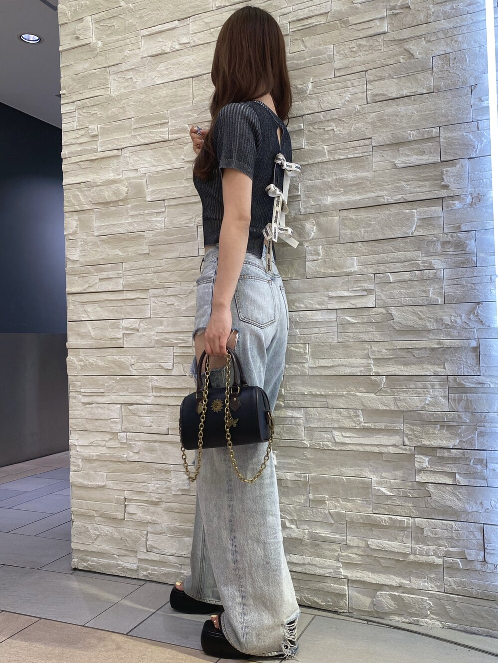 ブラック系のニット/セーター、ブルー系のデニムパンツ、その他のショルダーバッグを着用したレディースの夏コーディネートの2枚目の写真