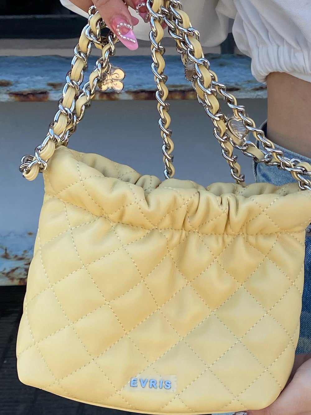 ブルー系のデニムパンツ、ホワイト系のシャツ/ブラウス、イエロー系のショルダーバッグを着用したレディースの春コーディネートの6枚目の写真