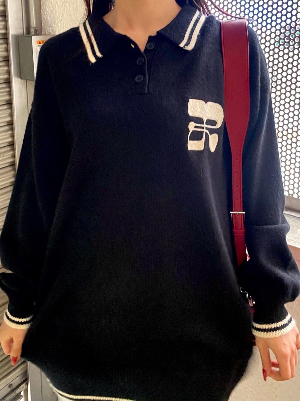 ブラック系のニット/セーター、レッド系のショルダーバッグ、グレー系のレッグウォーマーを着用したレディースの冬コーディネートの4枚目の写真