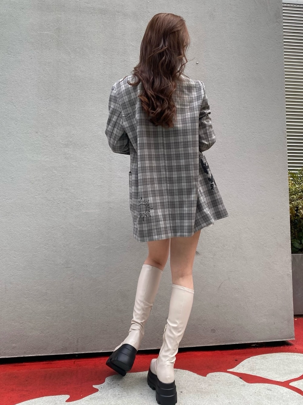 グレー系のテーラードジャケット、ブラック系のデニムスカート、ブラック系のブーツを着用したレディースの冬コーディネートの3枚目の写真