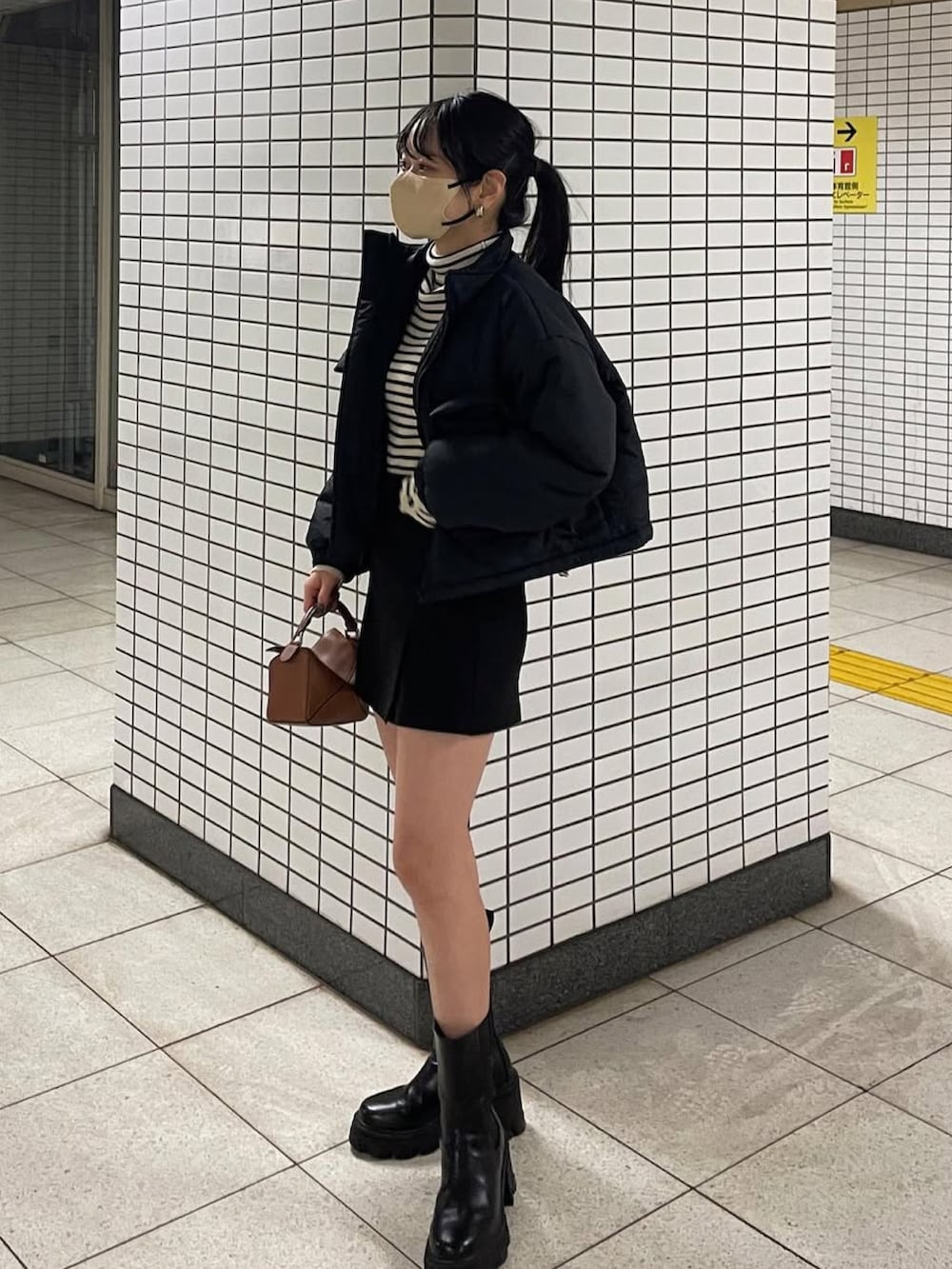 ブラック系のジャケット/アウター、ブラック系のブーツ、ブラウン系のハンドバッグを着用したレディースの冬コーディネートの2枚目の写真