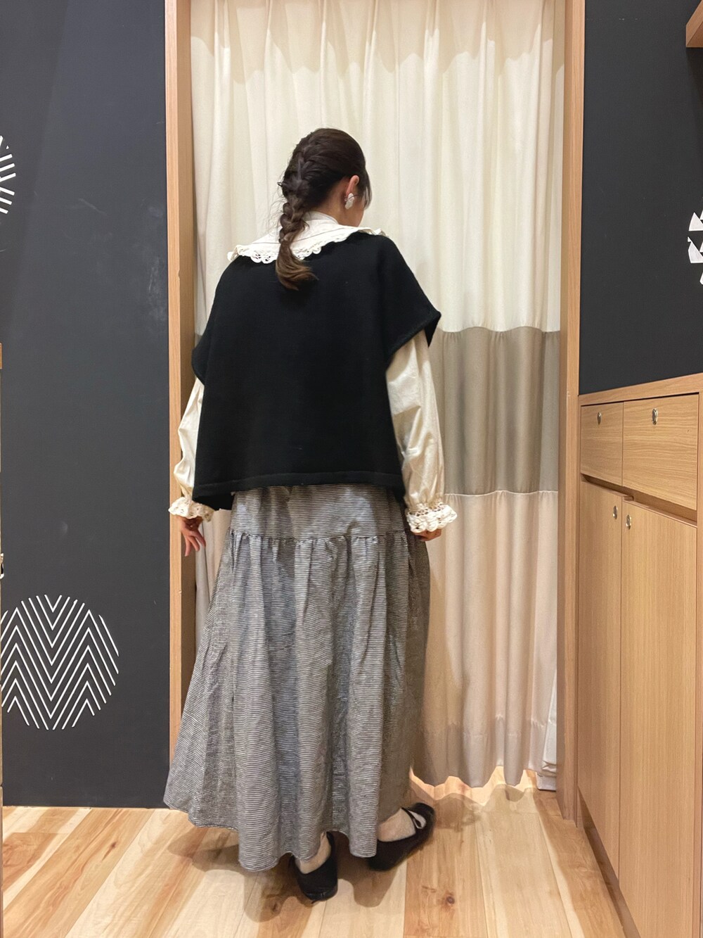 グレー系のスカート、ブラック系のベスト、ベージュ系のシャツ/ブラウスを着用したレディースの春コーディネートの2枚目の写真