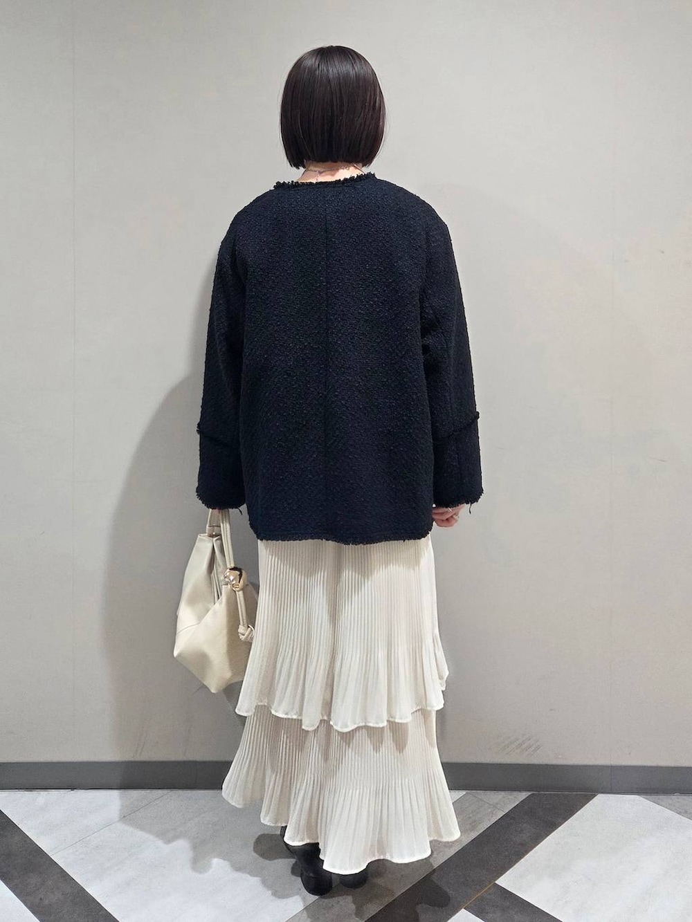 ホワイト系のスカート、ブラック系のローファー、ブルー系のノーカラージャケットを着用したレディースの冬コーディネートの3枚目の写真