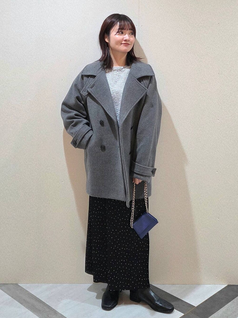グレー系のピーコート、その他のスカート、ブラック系のブーツを着用したレディースの秋コーディネートの2枚目の写真