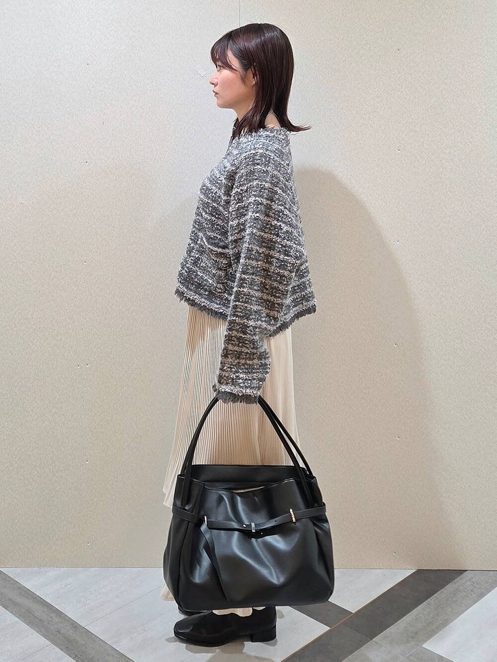 ホワイト系のスカート、ブラック系のブーツ、グレー系のカーディガン/ボレロを着用したレディースの秋コーディネートの3枚目の写真