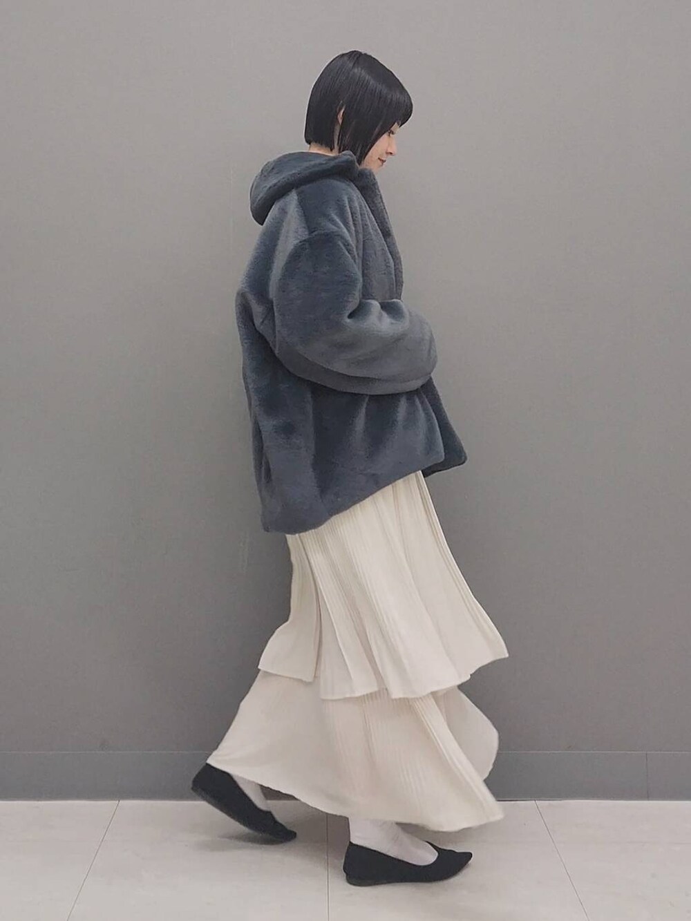 ベージュ系のスカート、グレー系のその他アウター、ホワイト系のニット/セーターを着用したレディースの冬コーディネートの2枚目の写真