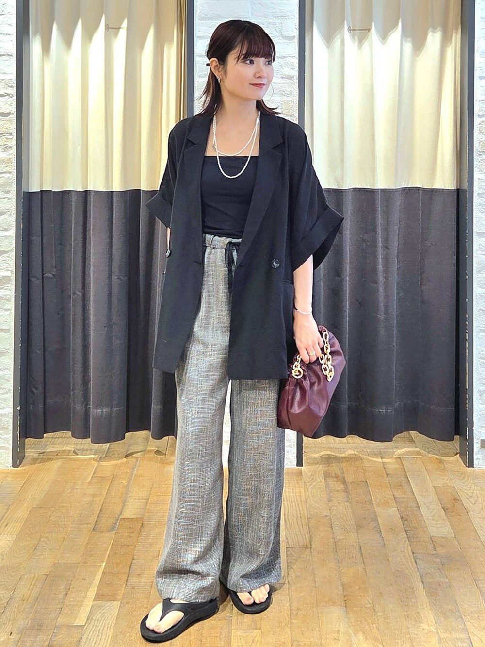 ブラック系のスラックス、レッド系のショルダーバッグ、ブラック系のサンダルを着用したレディースの秋コーディネートの2枚目の写真