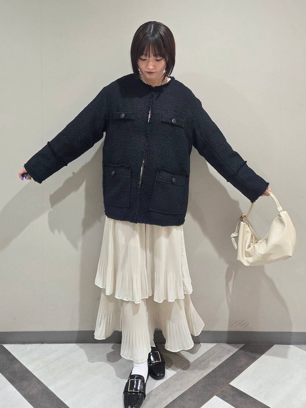 ホワイト系のスカート、ブラック系のローファー、ブルー系のノーカラージャケットを着用したレディースの冬コーディネートの4枚目の写真