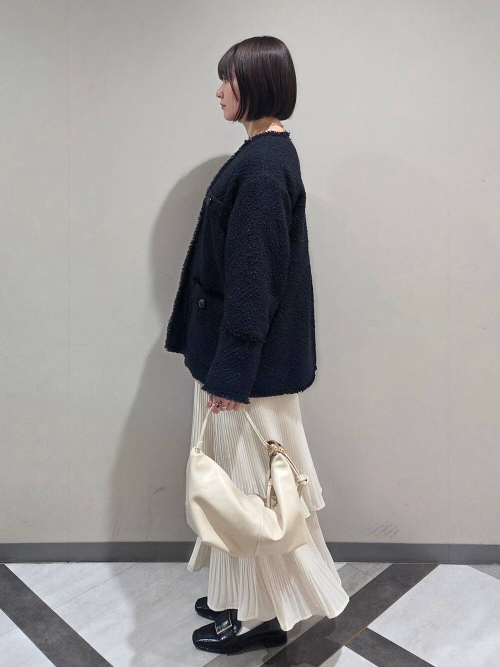 ホワイト系のスカート、ブラック系のローファー、ブルー系のノーカラージャケットを着用したレディースの冬コーディネートの2枚目の写真