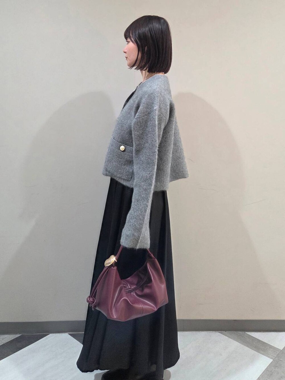 グレー系のカーディガン/ボレロ、ブラック系のブーツ、ベージュ系のショルダーバッグを着用したレディースの秋コーディネートの2枚目の写真