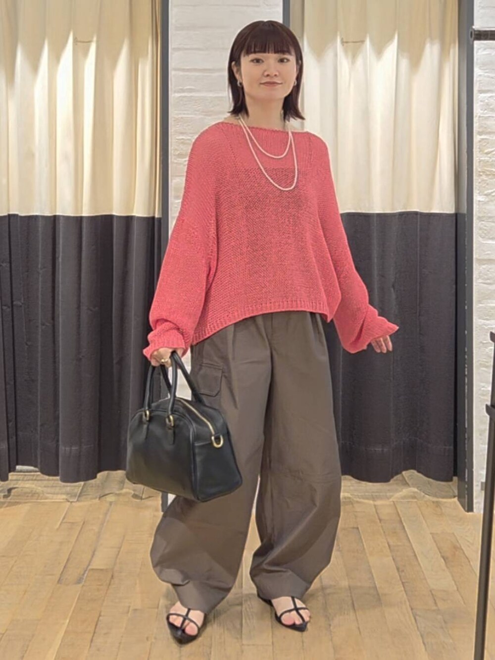 ブラック系のサンダル、ブラック系のボストンバッグ、ピンク系のニット/セーターを着用したレディースの夏コーディネートの7枚目の写真