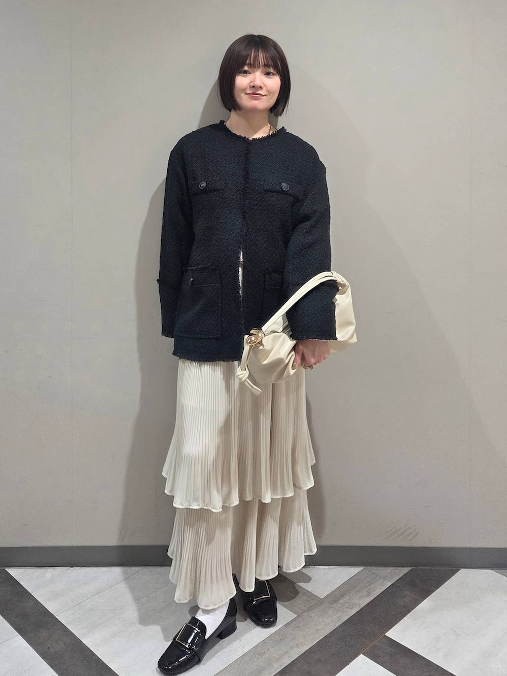 ホワイト系のスカート、ブラック系のローファー、ブルー系のノーカラージャケットを着用したレディースの冬コーディネートの5枚目の写真