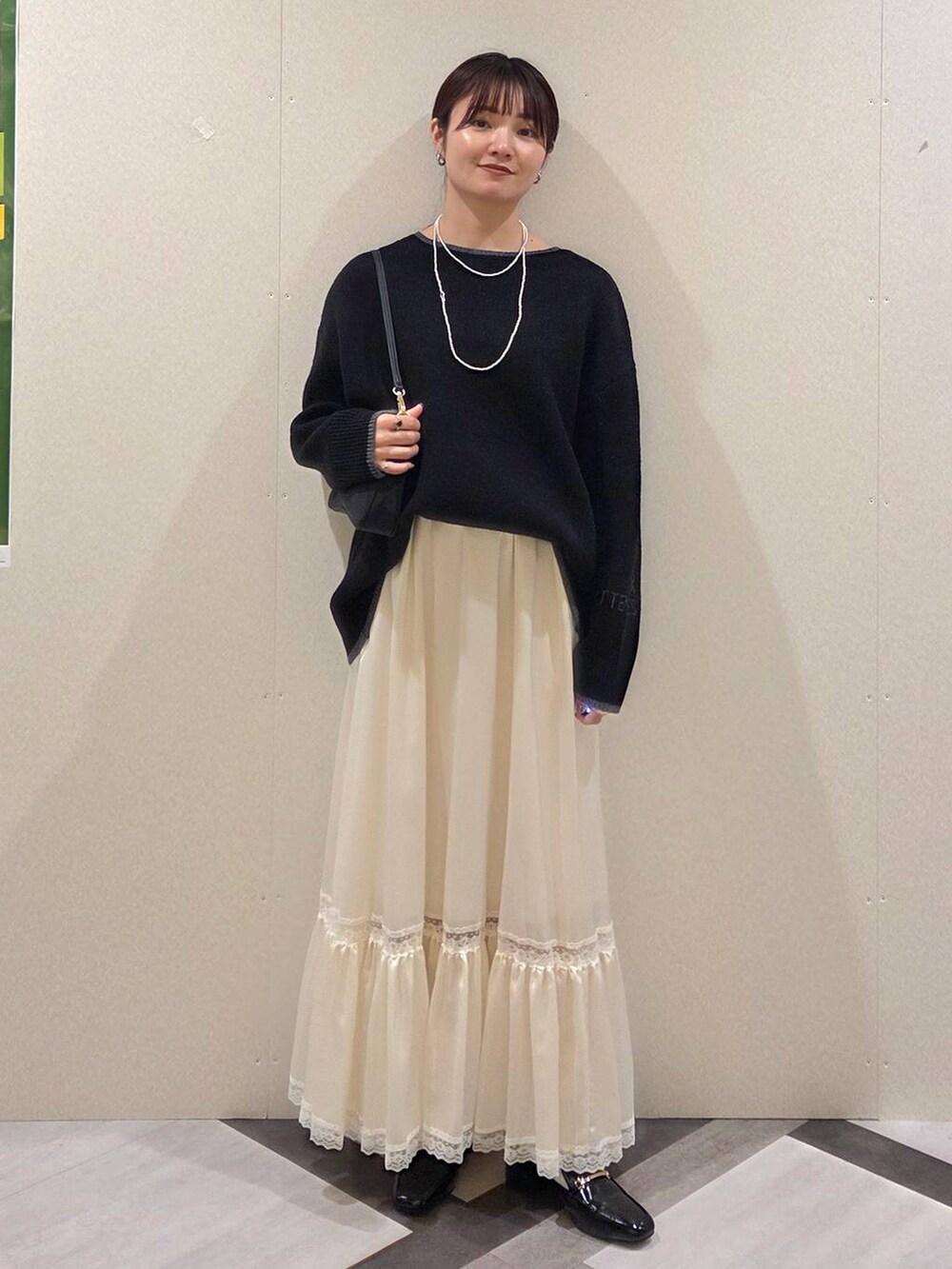 ブラック系のローファー、ブラック系のショルダーバッグ、ホワイト系のスカートを着用したレディースの秋コーディネートの5枚目の写真