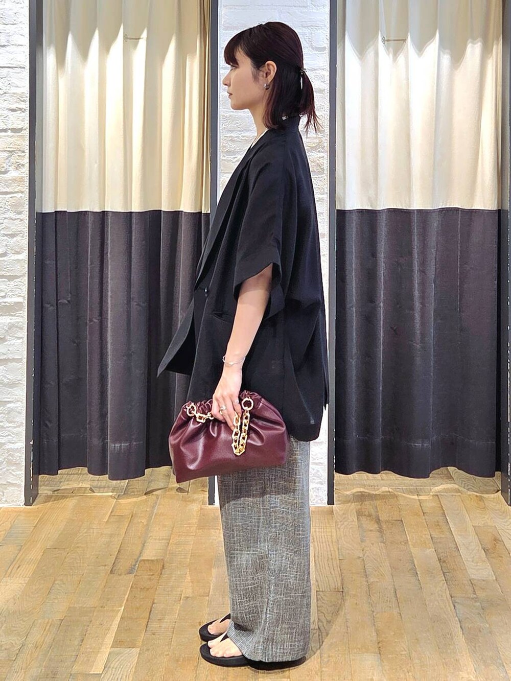 ブラック系のスラックス、レッド系のショルダーバッグ、ブラック系のサンダルを着用したレディースの秋コーディネートの3枚目の写真