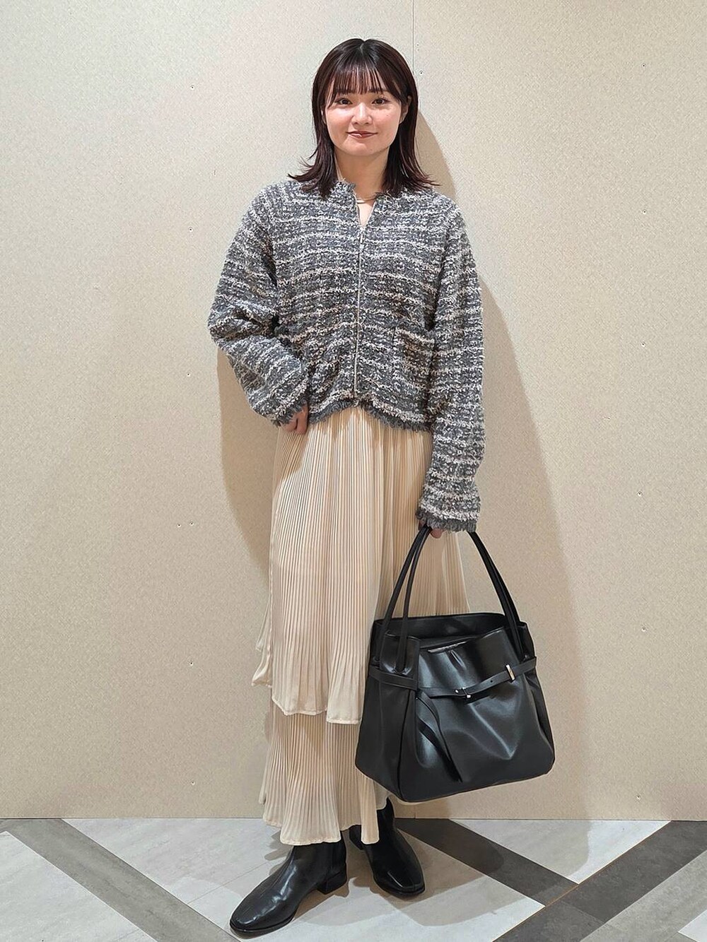 ホワイト系のスカート、ブラック系のブーツ、グレー系のカーディガン/ボレロを着用したレディースの秋コーディネートの6枚目の写真