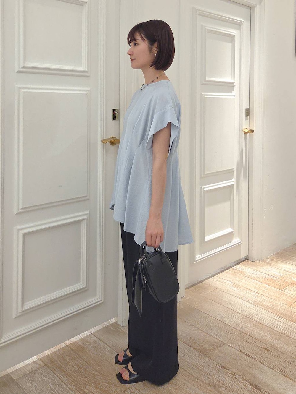 ブルー系のシャツ/ブラウス、ブラック系のスラックス、ブラック系のパンプスを着用したレディースの夏コーディネートの2枚目の写真