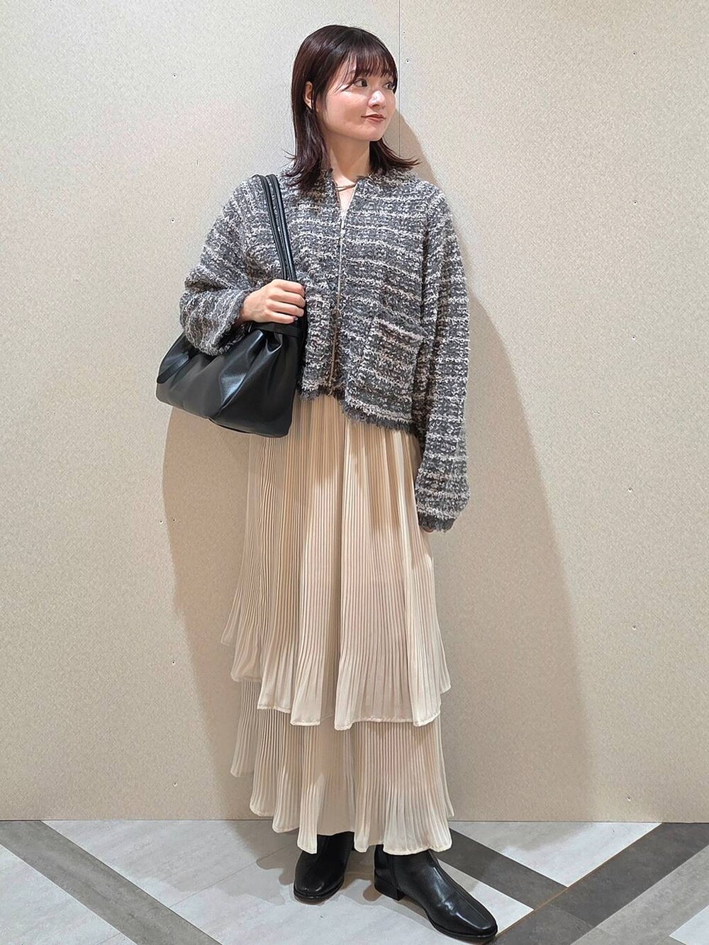 ホワイト系のスカート、ブラック系のブーツ、グレー系のカーディガン/ボレロを着用したレディースの秋コーディネートの2枚目の写真