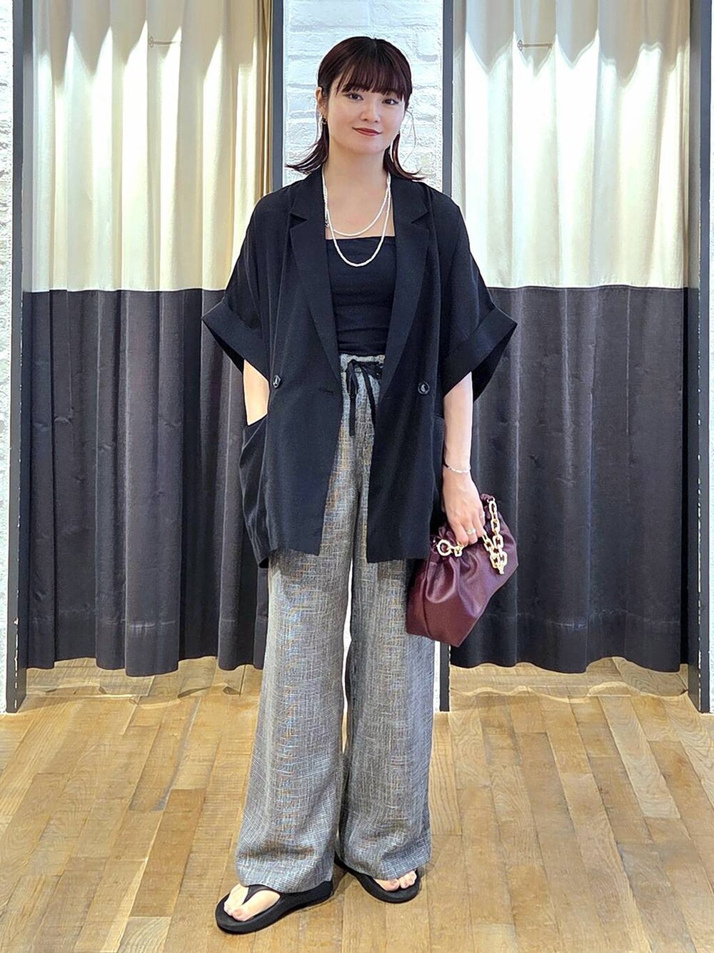 ブラック系のスラックス、レッド系のショルダーバッグ、ブラック系のサンダルを着用したレディースの秋コーディネートの5枚目の写真