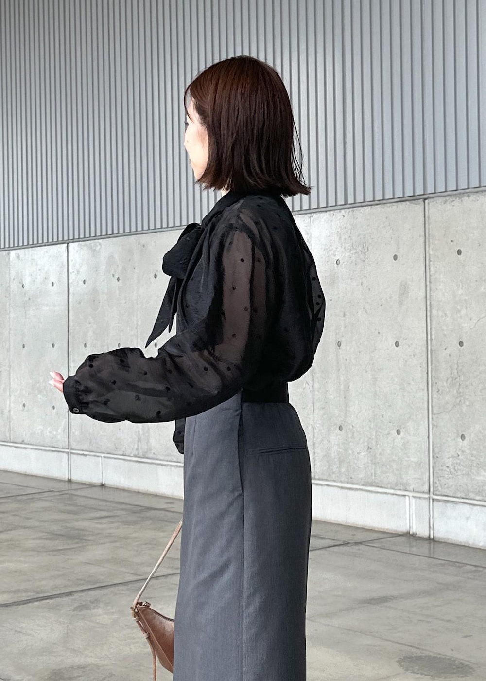 ベージュ系のハンドバッグ、グレー系のスカート、ブラック系のシャツ/ブラウスを着用したレディースの秋コーディネートの4枚目の写真