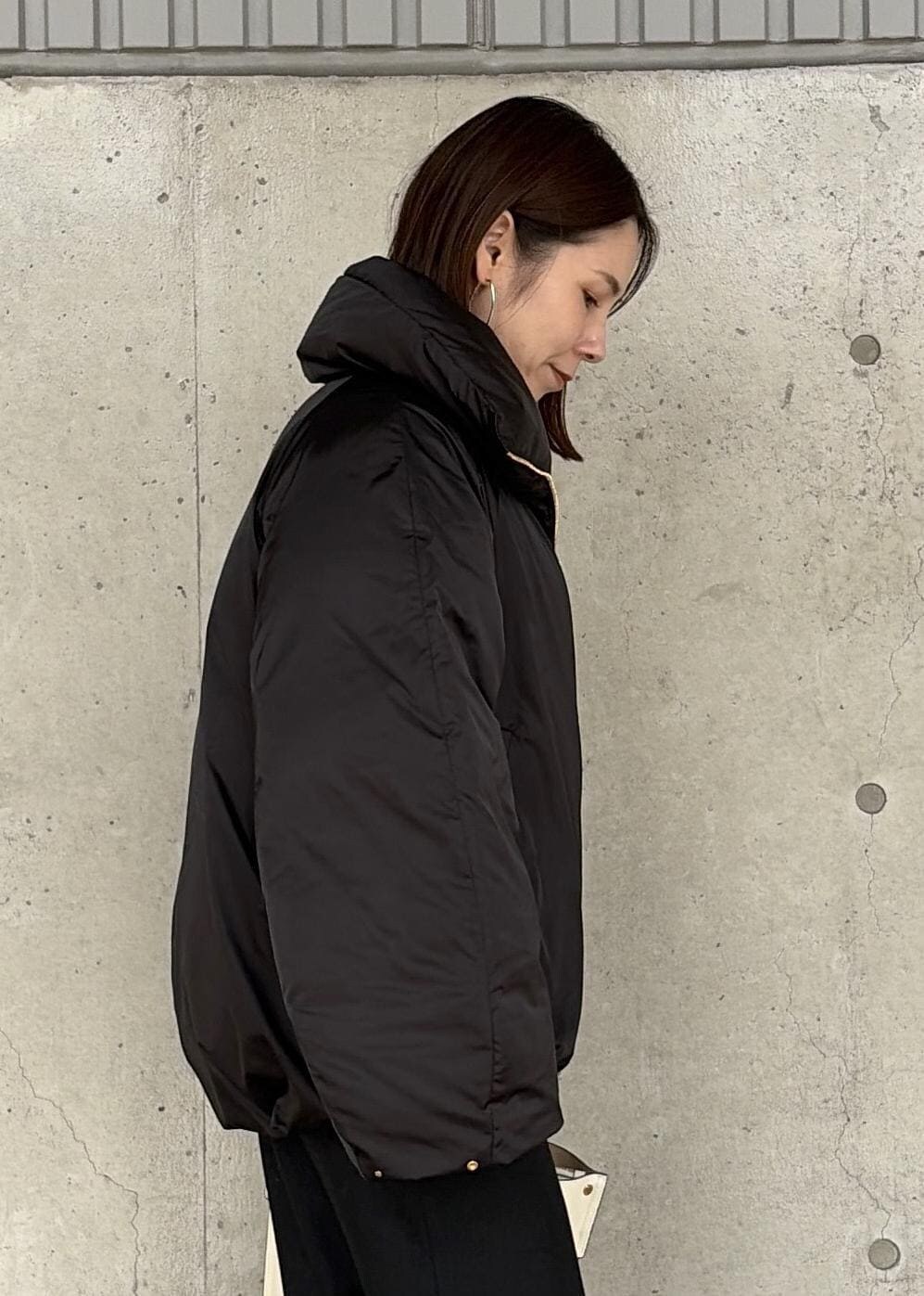 ホワイト系のハンドバッグ、ブラック系のブーツ、ブラック系のスカートを着用したレディースの秋コーディネートの4枚目の写真