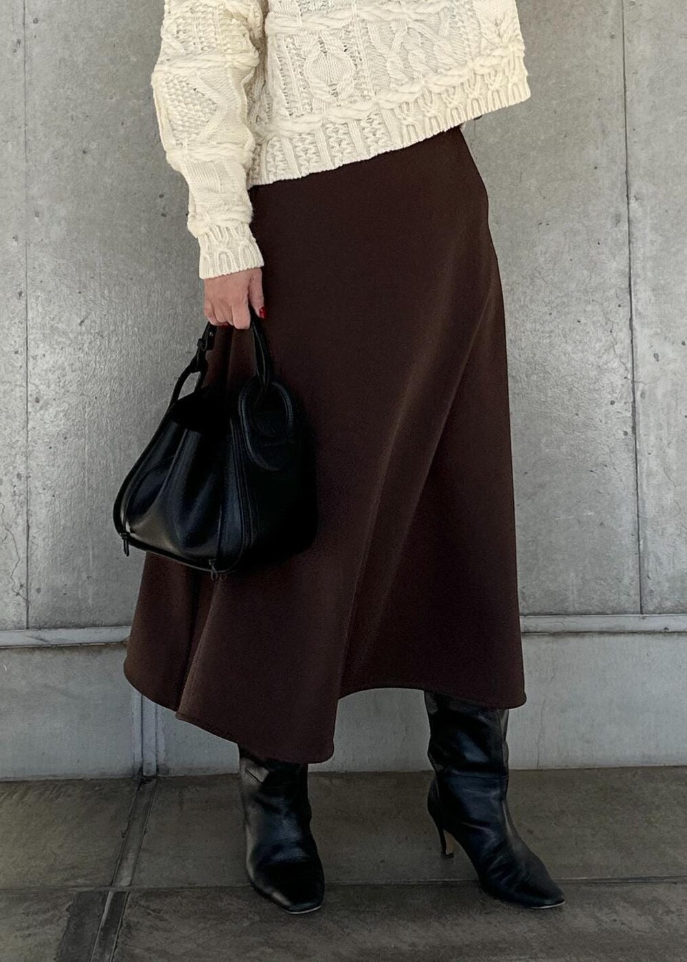 ブラック系のハンドバッグ、ブラウン系のスカート、ホワイト系のニット/セーターを着用したレディースの冬コーディネートの6枚目の写真