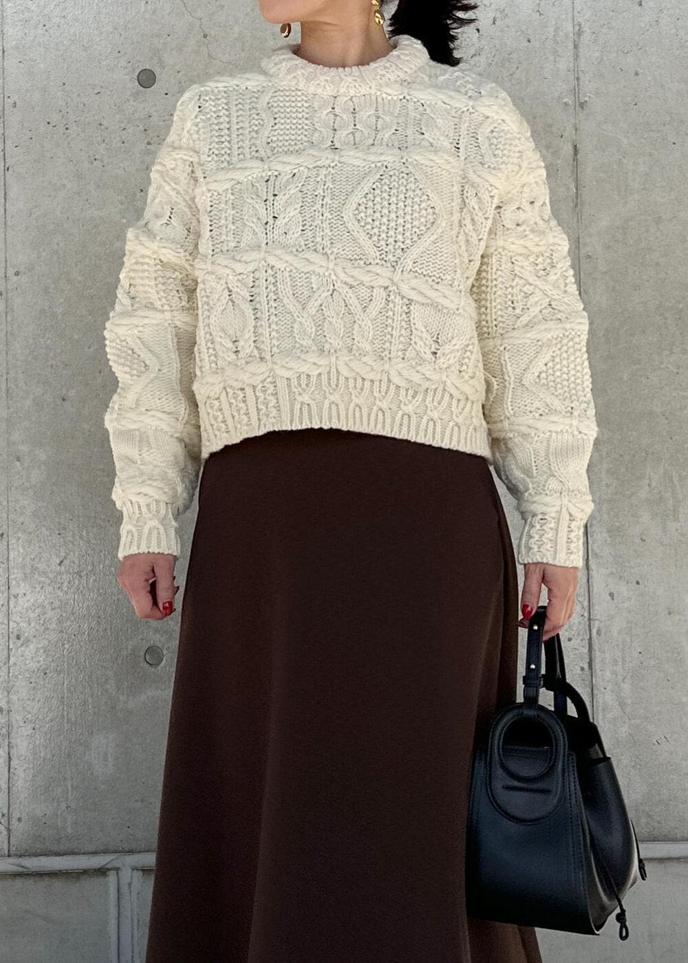 ブラック系のハンドバッグ、ブラウン系のスカート、ホワイト系のニット/セーターを着用したレディースの冬コーディネートの5枚目の写真