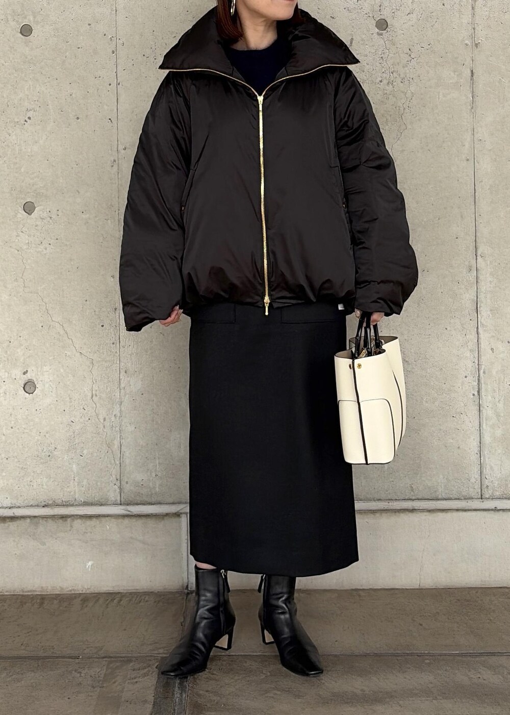 ホワイト系のハンドバッグ、ブラック系のブーツ、ブラック系のスカートを着用したレディースの秋コーディネートの5枚目の写真