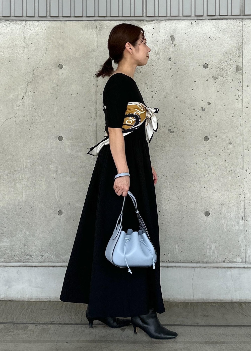 ホワイト系のデニムジャケット、ブルー系のハンドバッグ、ブラック系のワンピースを着用したレディースの秋コーディネートの4枚目の写真