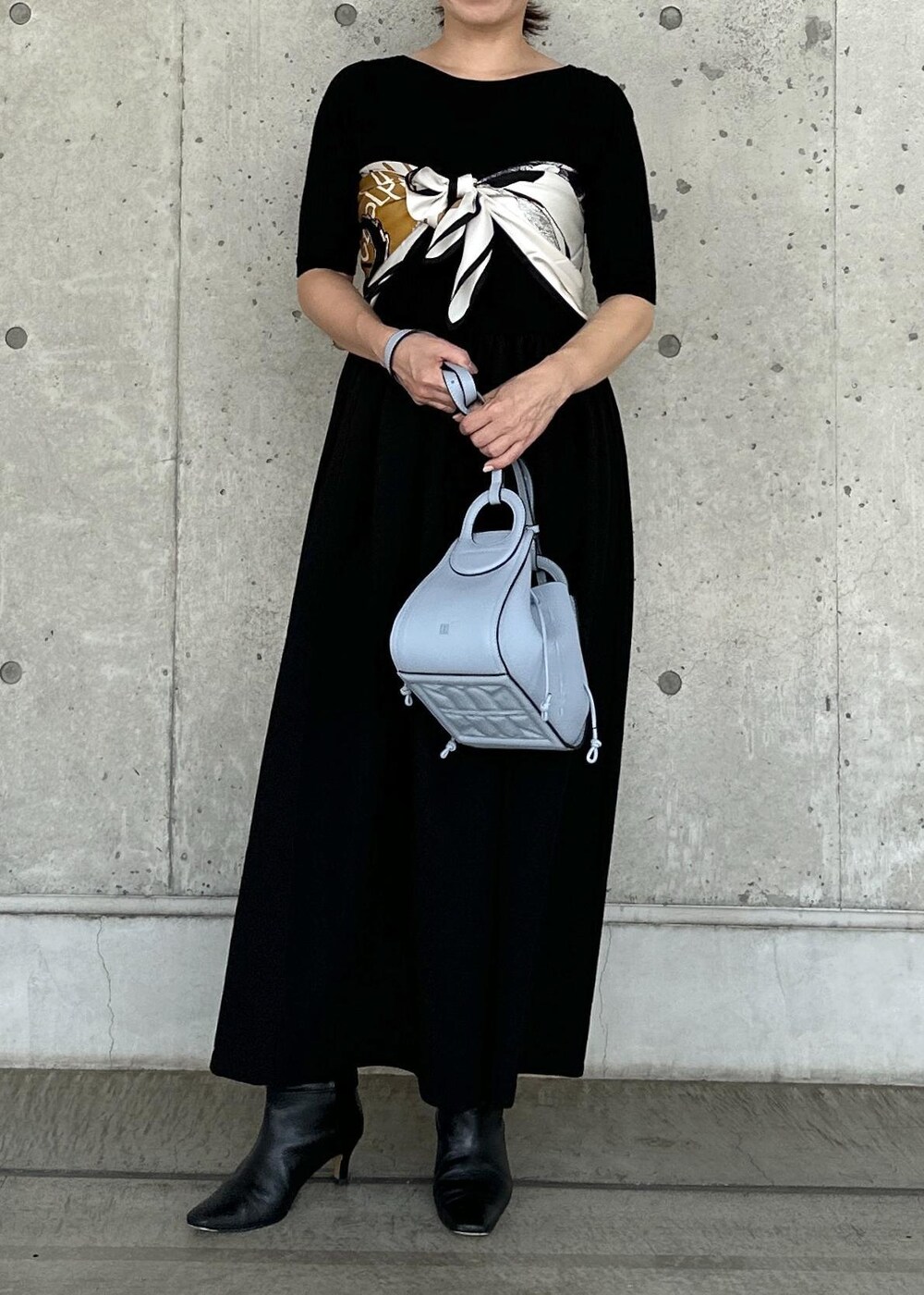 ホワイト系のデニムジャケット、ブルー系のハンドバッグ、ブラック系のワンピースを着用したレディースの秋コーディネートの7枚目の写真