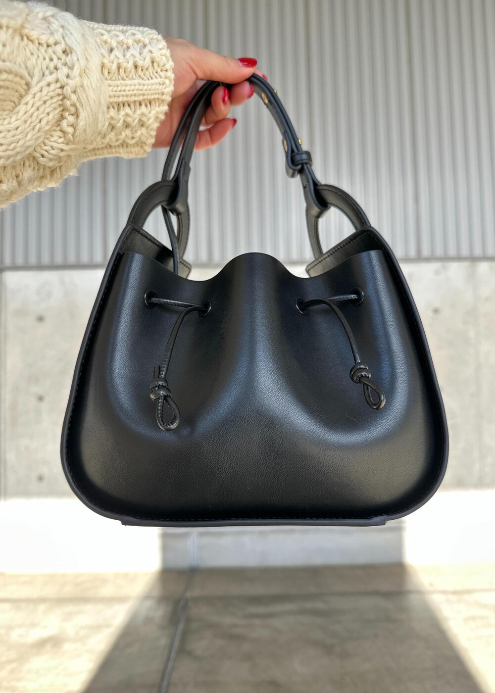 ブラック系のハンドバッグ、ブラウン系のスカート、ホワイト系のニット/セーターを着用したレディースの冬コーディネートの7枚目の写真