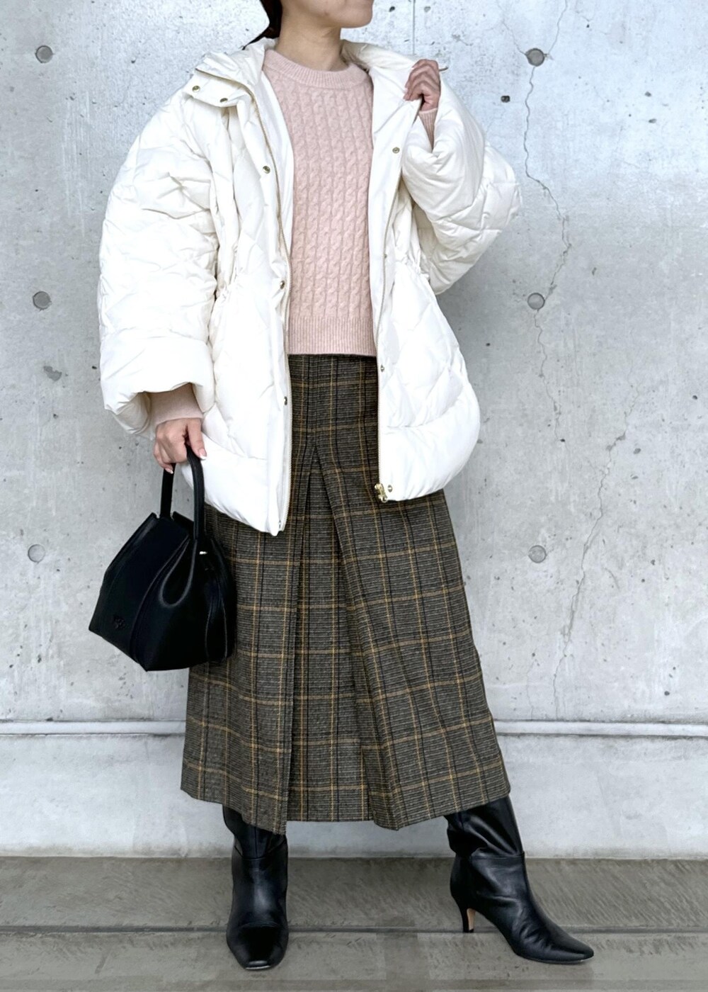 ブラック系のハンドバッグ、ブラック系のブーツ、ホワイト系のダウンジャケット/コートを着用したレディースの秋コーディネートの6枚目の写真