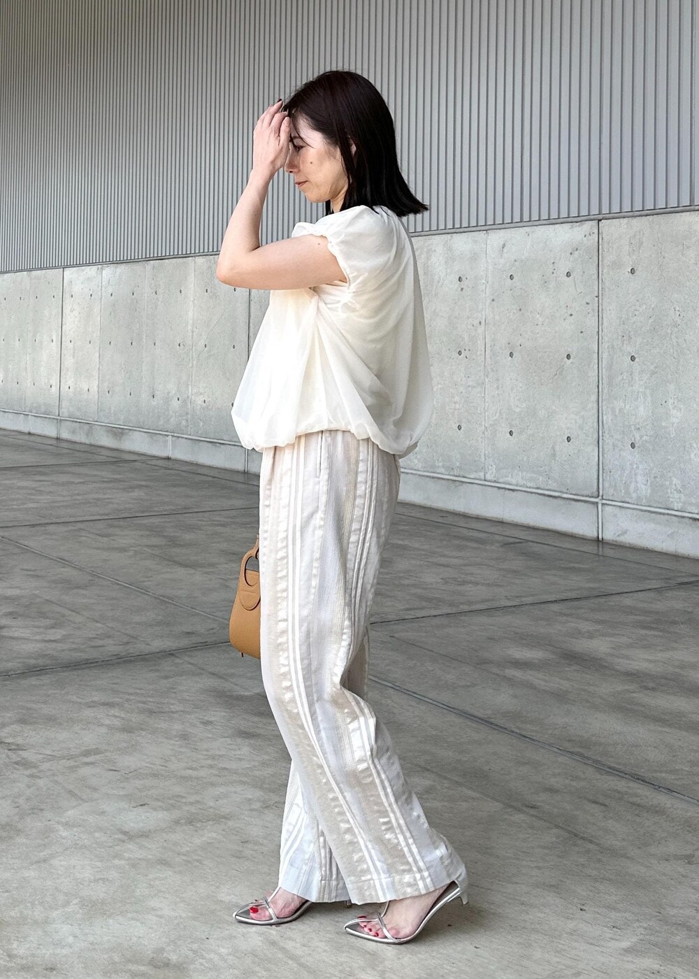 ホワイト系のTシャツ/カットソー、ベージュ系のその他パンツ、イエロー系のハンドバッグを着用したレディースの夏コーディネートの2枚目の写真