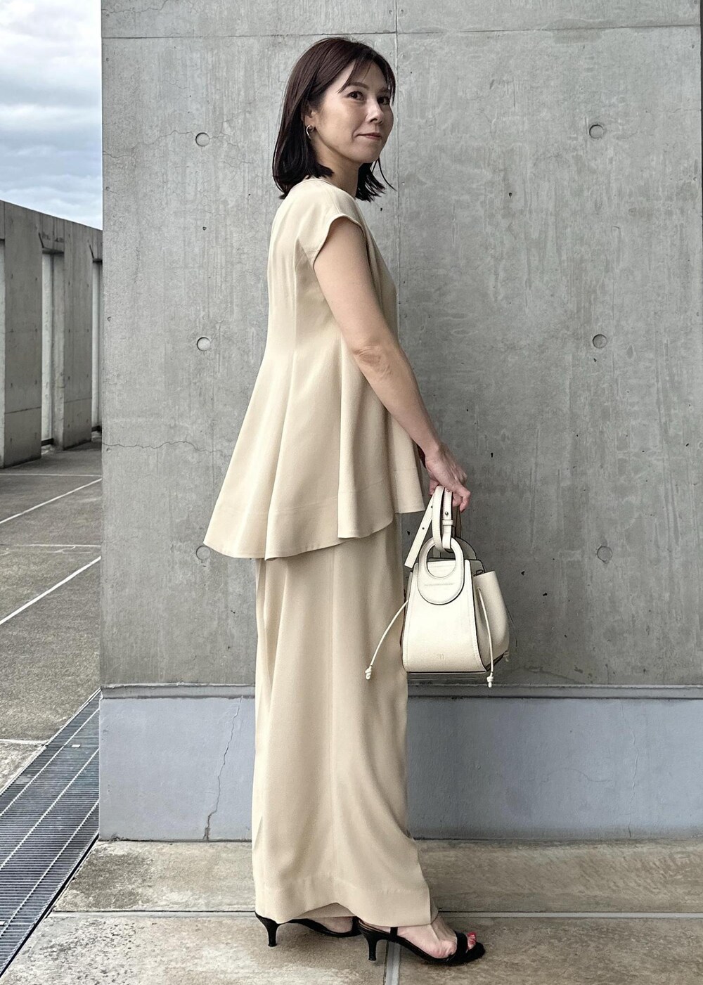 ホワイト系のハンドバッグ、ベージュ系のシャツ/ブラウス、ベージュ系のその他パンツを着用したレディースの夏コーディネートの2枚目の写真