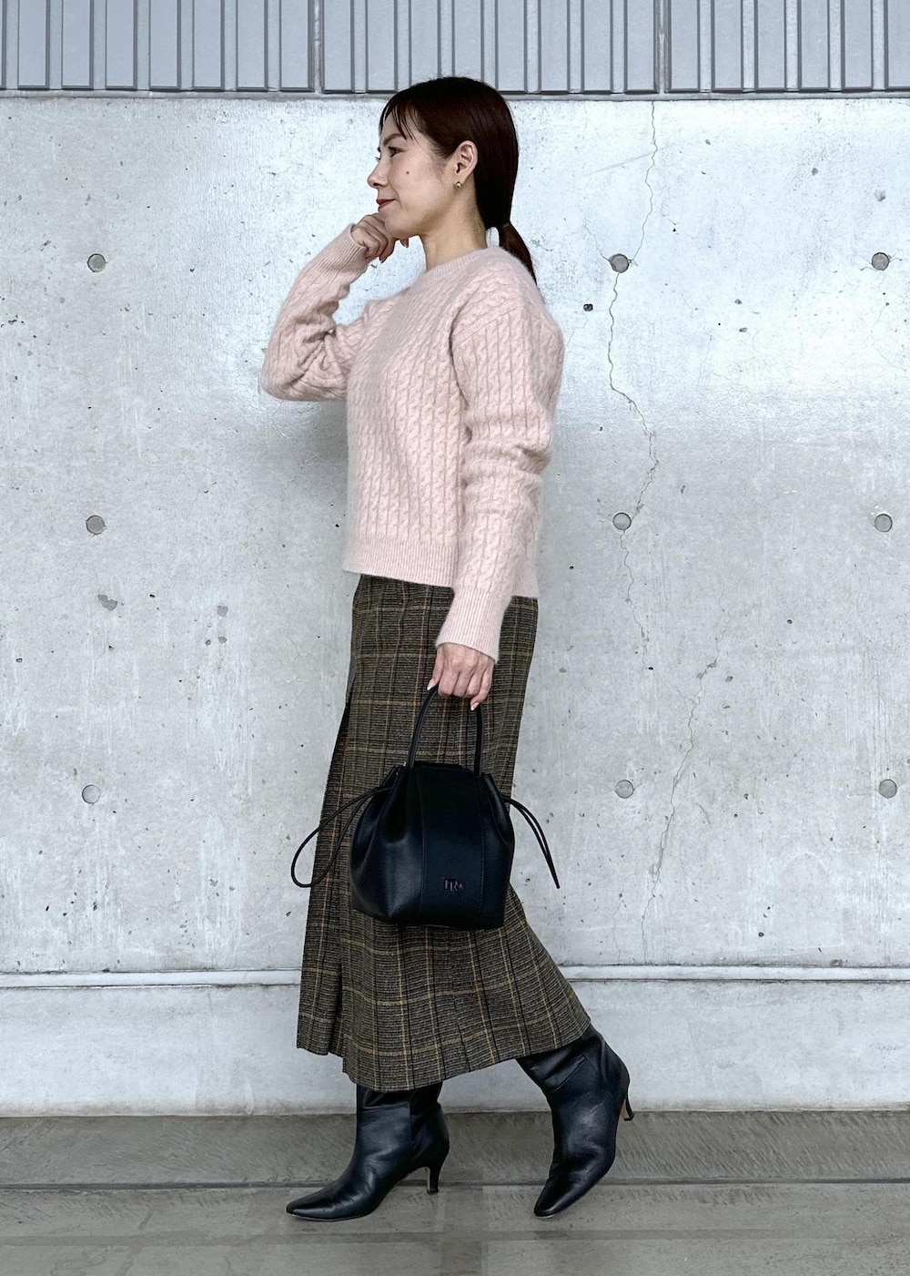 ブラック系のハンドバッグ、ブラック系のブーツ、ホワイト系のダウンジャケット/コートを着用したレディースの秋コーディネートの3枚目の写真