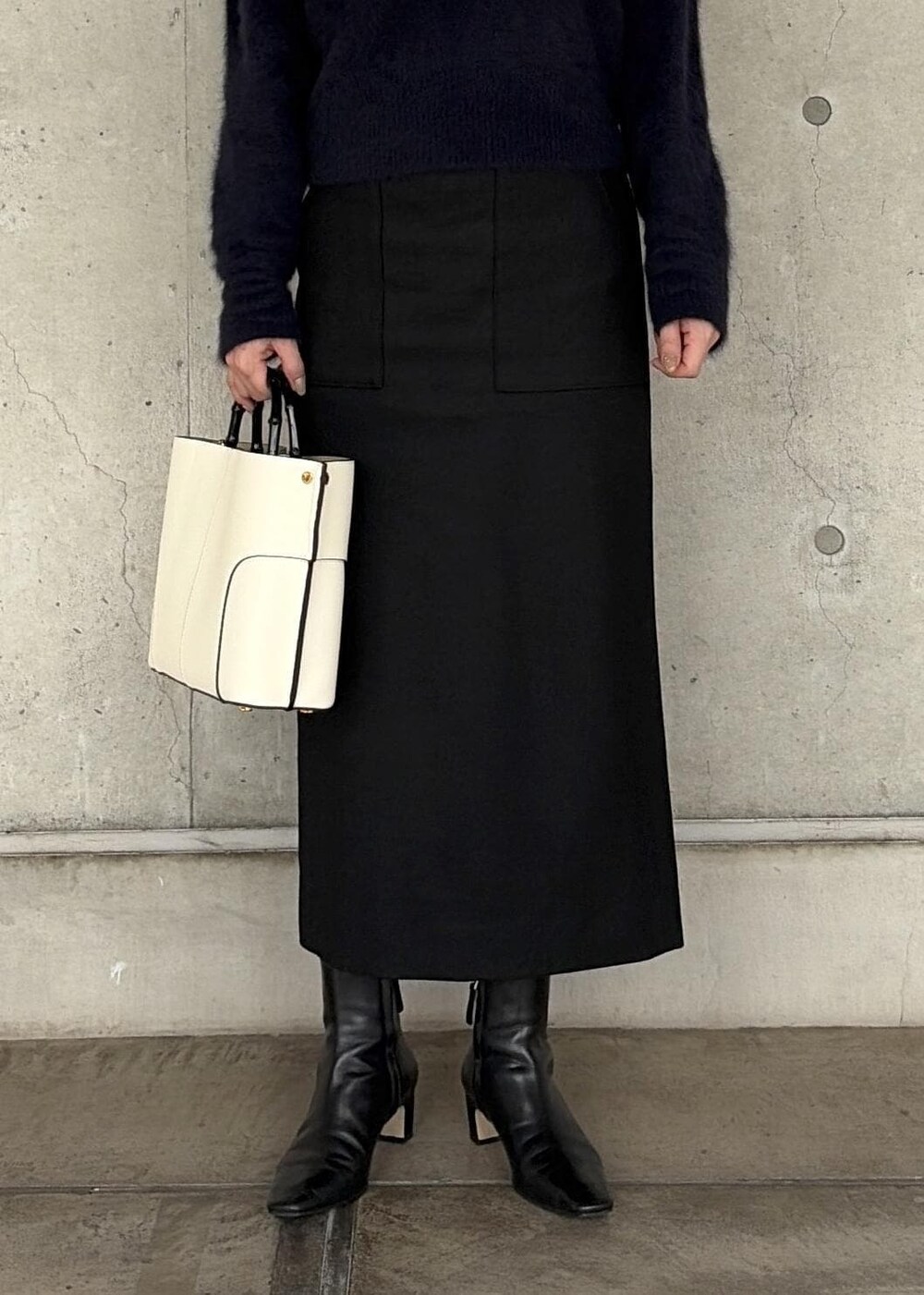 ホワイト系のハンドバッグ、ブラック系のブーツ、ブラック系のスカートを着用したレディースの秋コーディネートの6枚目の写真
