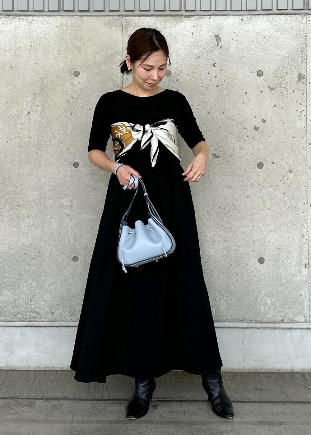 ホワイト系のデニムジャケット、ブルー系のハンドバッグ、ブラック系のワンピースを着用したレディースの秋コーディネートの3枚目の写真