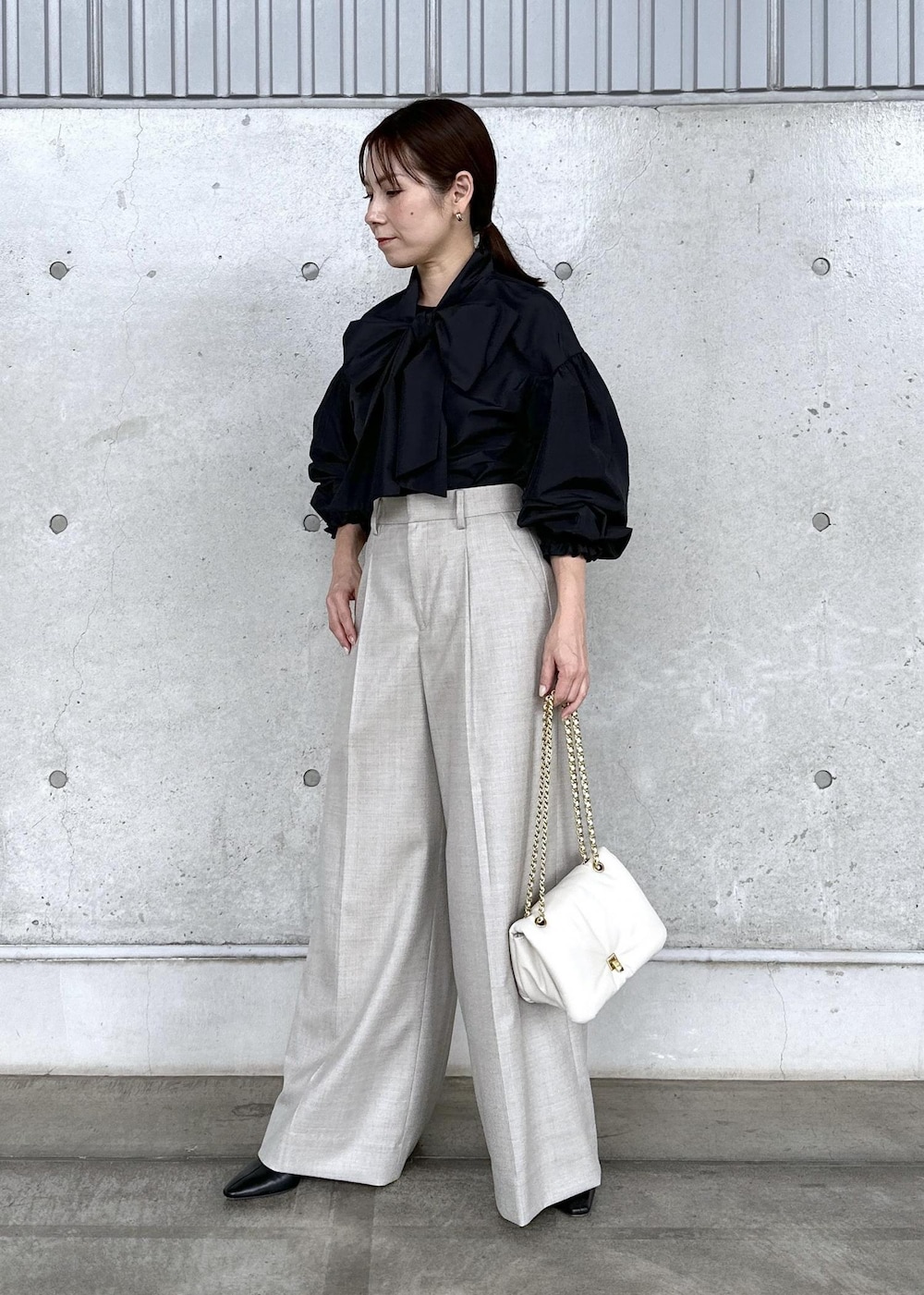 ブラック系のブーツ、ホワイト系のハンドバッグ、ベージュ系のその他パンツを着用したレディースの秋コーディネートの2枚目の写真