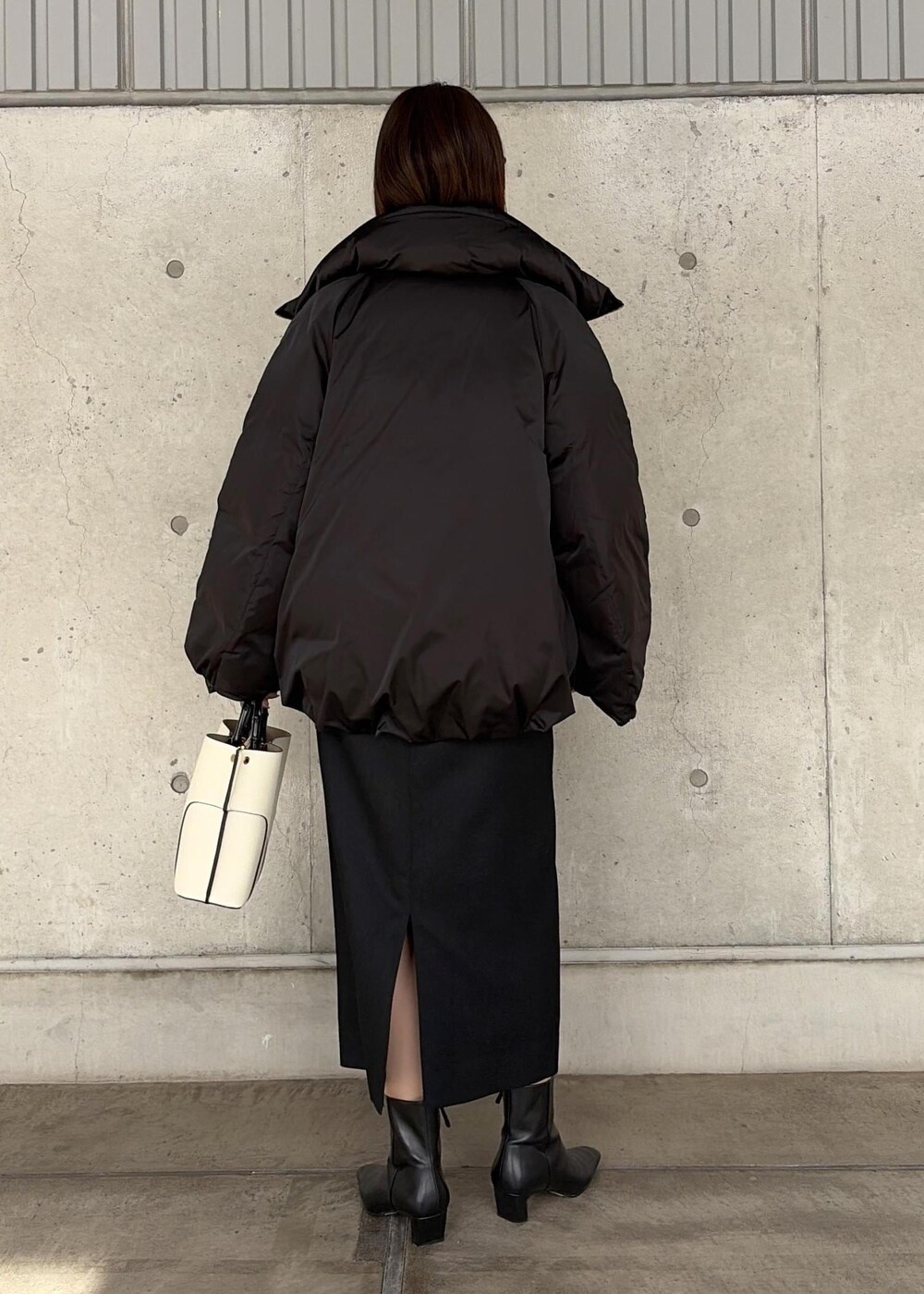 ホワイト系のハンドバッグ、ブラック系のブーツ、ブラック系のスカートを着用したレディースの秋コーディネートの3枚目の写真