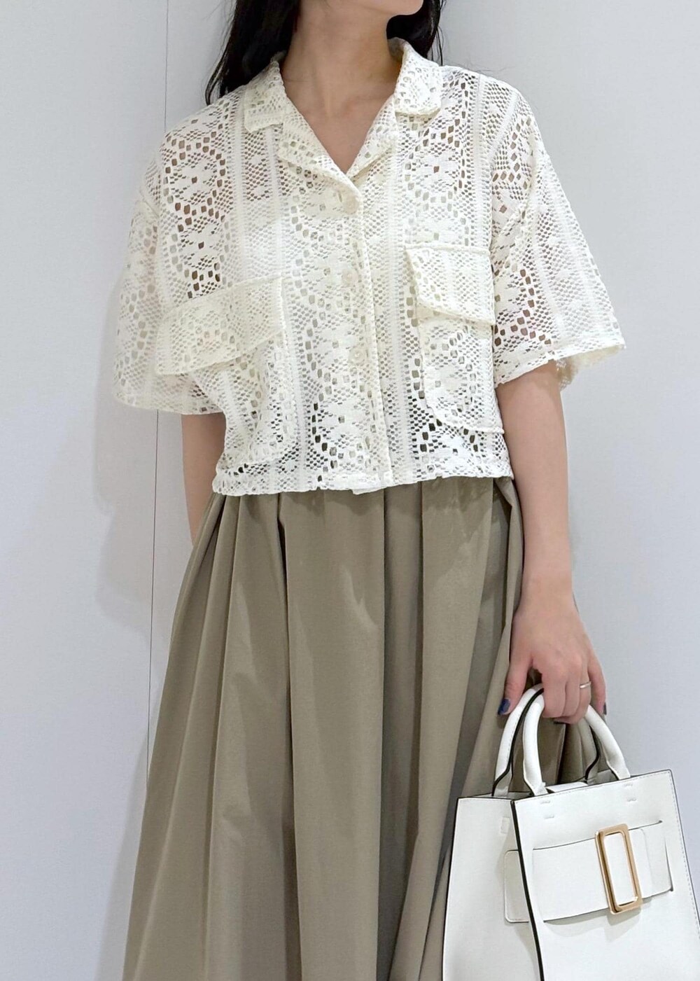 ホワイト系のサンダル、ホワイト系のハンドバッグ、グリーン系のスカートを着用したレディースの夏コーディネートの4枚目の写真