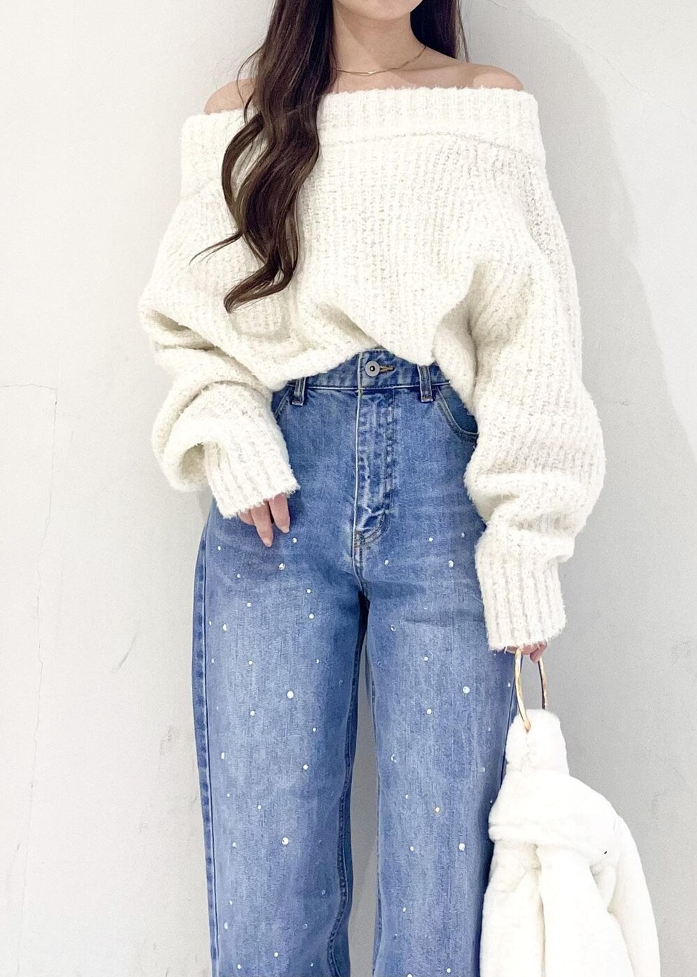 ホワイト系のハンドバッグ、ブルー系のデニムパンツ、シルバー系のパンプスを着用したレディースの秋コーディネートの4枚目の写真