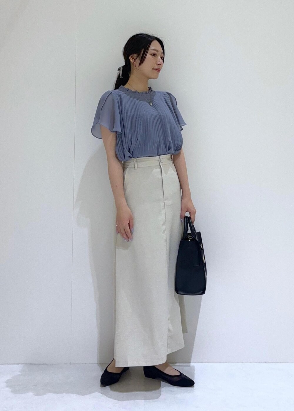 ブラック系のパンプス、ホワイト系のスカート、ブルー系のシャツ/ブラウスを着用したレディースの夏コーディネートの2枚目の写真