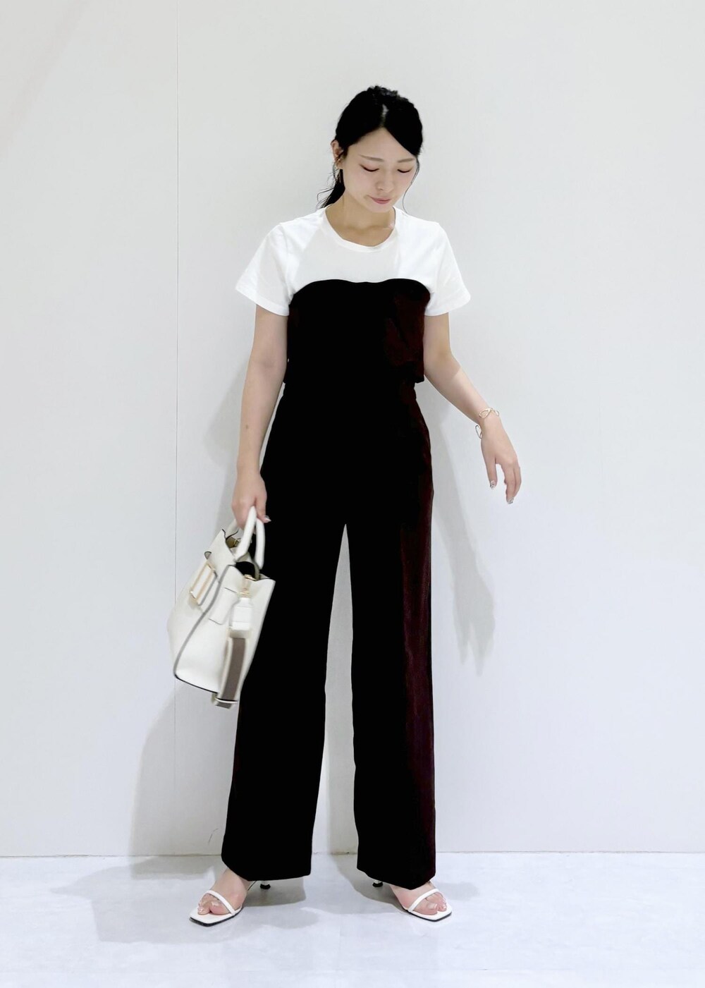 ホワイト系のサンダル、ホワイト系のハンドバッグ、ブラウン系のTシャツ/カットソーを着用したレディースの夏コーディネートの2枚目の写真