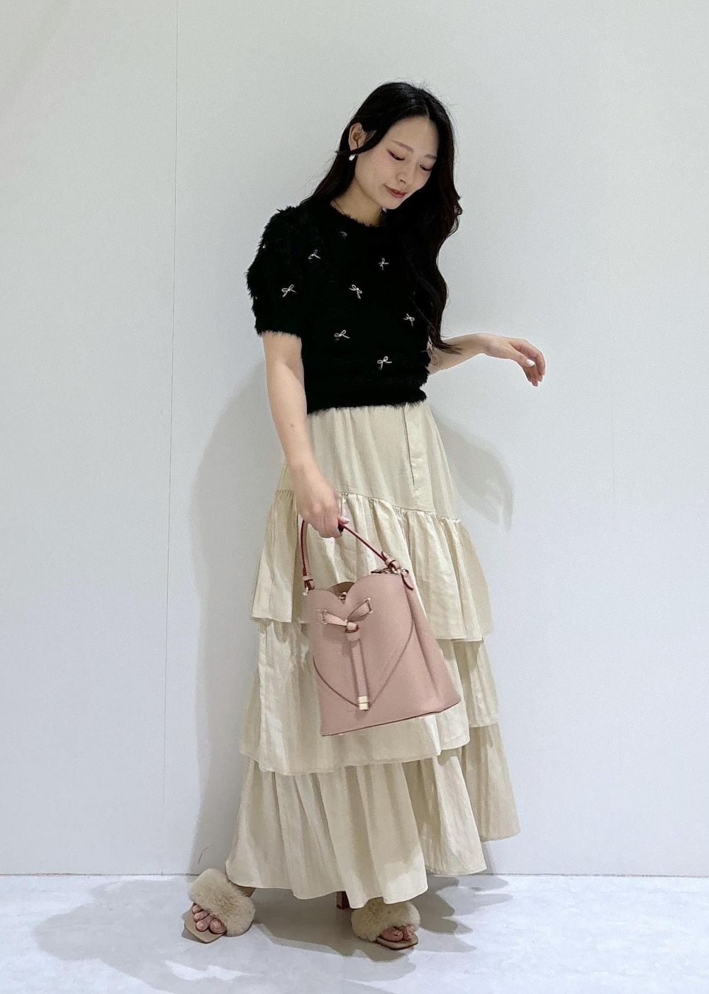 ベージュ系のドレスシューズ、ベージュ系のスカート、ブラック系のニット/セーターを着用したレディースの夏コーディネートの2枚目の写真