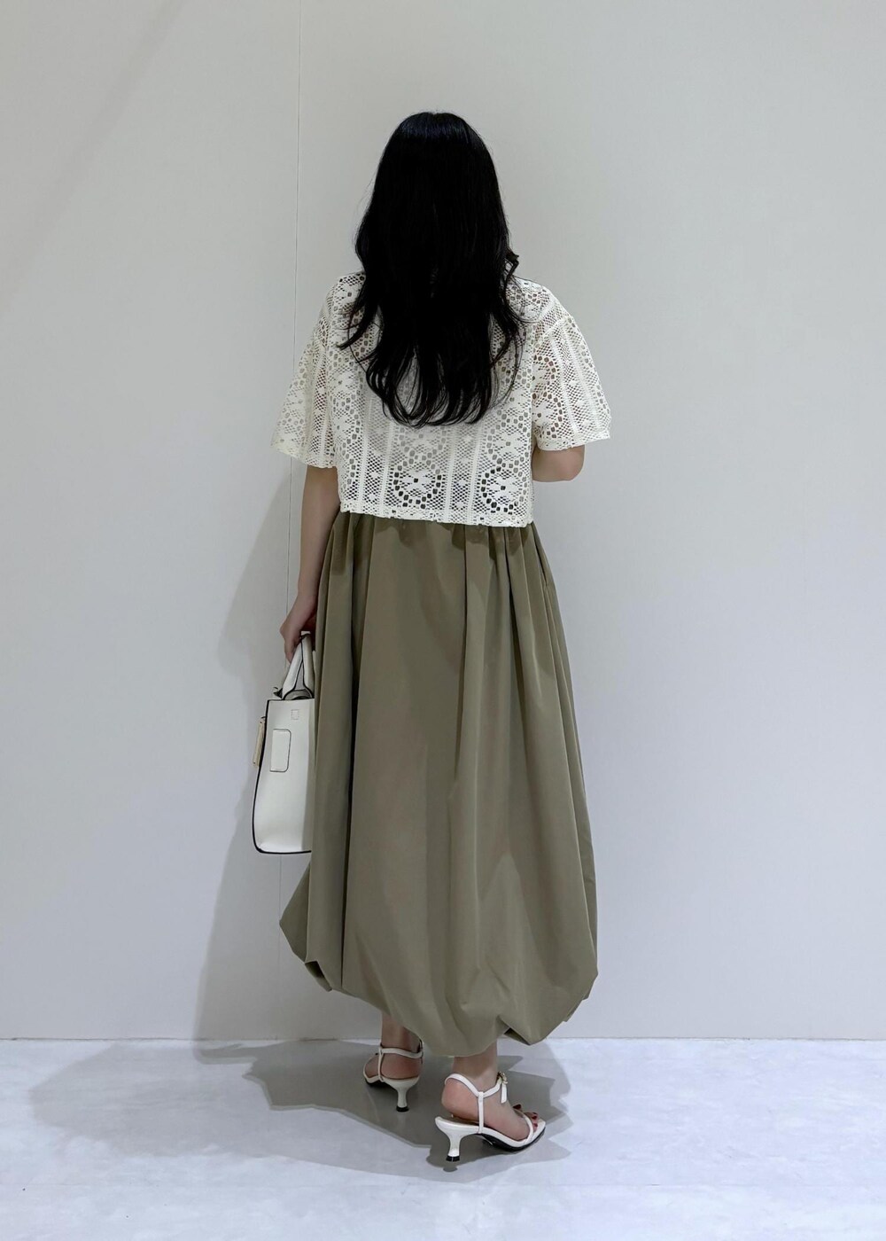 ホワイト系のサンダル、ホワイト系のハンドバッグ、グリーン系のスカートを着用したレディースの夏コーディネートの3枚目の写真