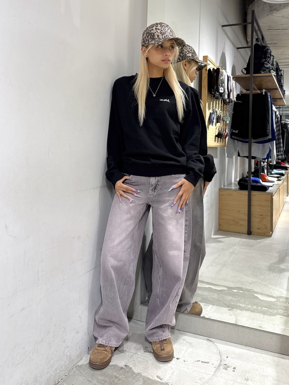 ピンク系のデニムパンツ、ブラック系のスウェット、ベージュ系のキャップを着用したレディースの秋コーディネートの2枚目の写真