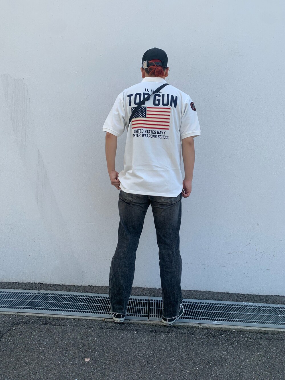 ホワイト系のポロシャツ、グリーン系のショルダーバッグを着用したメンズの夏コーディネートの2枚目の写真