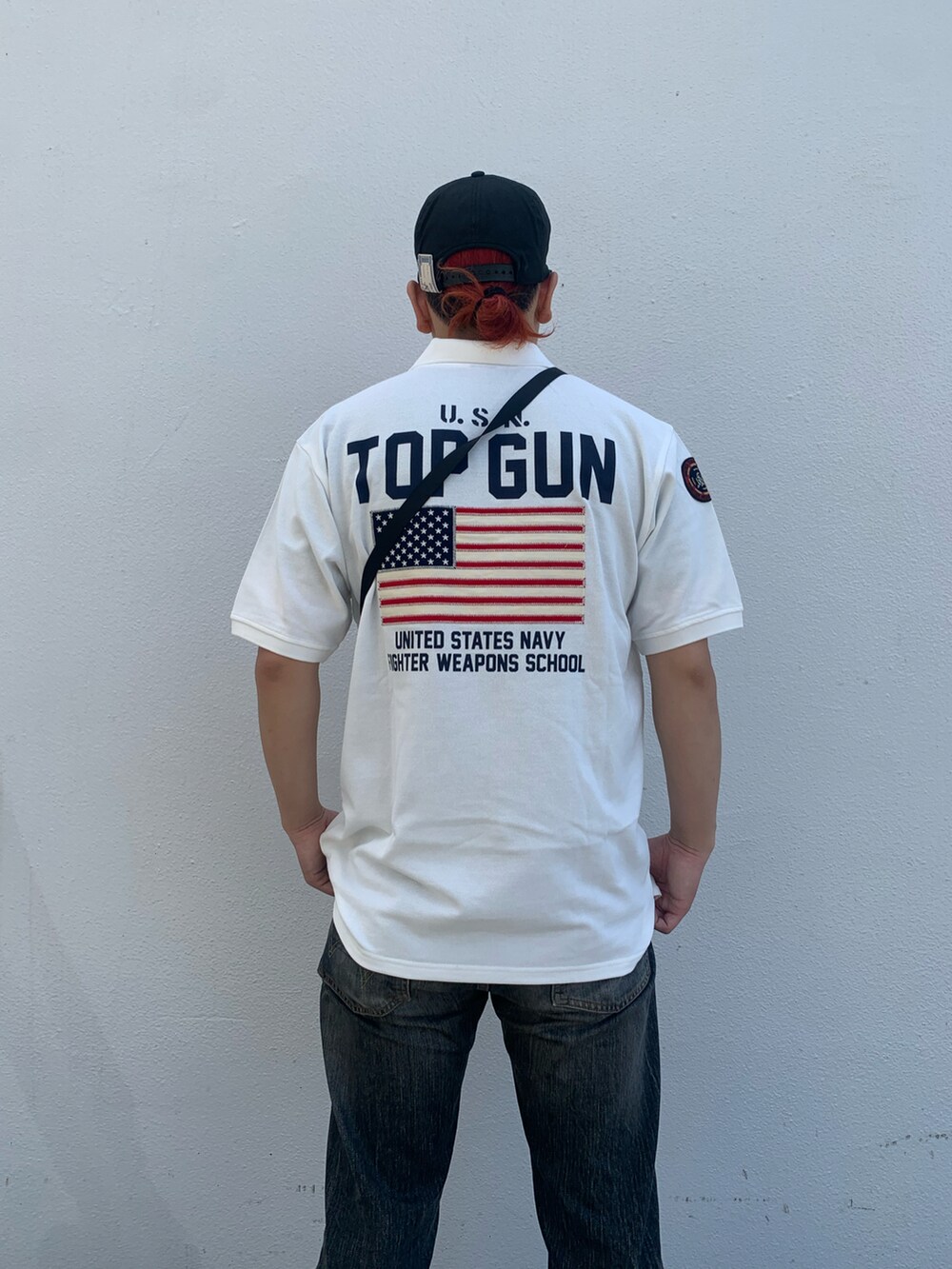 ホワイト系のポロシャツ、グリーン系のショルダーバッグを着用したメンズの夏コーディネートの3枚目の写真